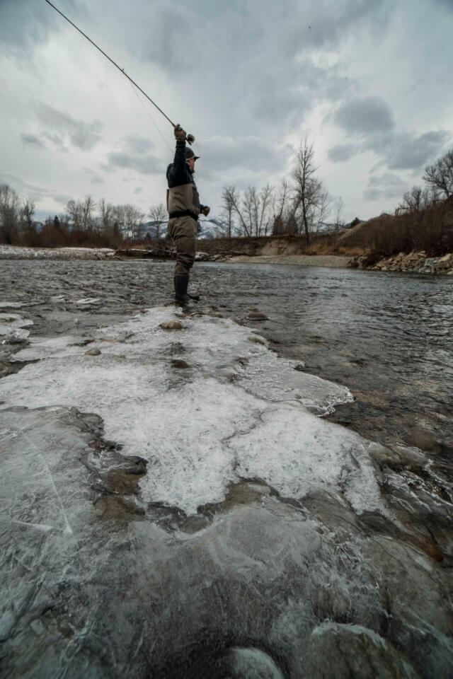 Fly fisherman casting to river.